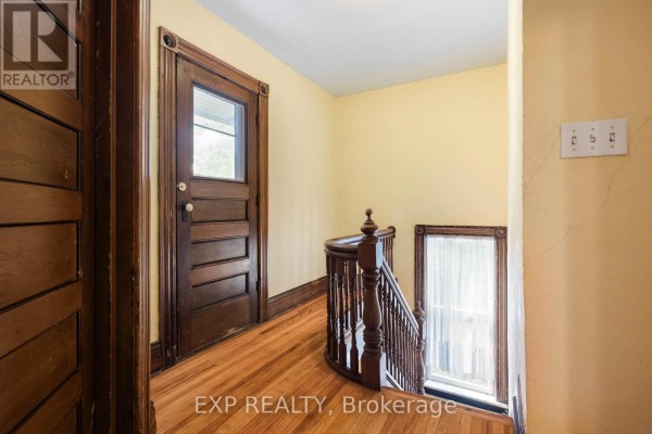 Wooden staircase with wooden banister and trim, leading to a hallway with yellow walls. - Upper - 52 First Street, Orangeville