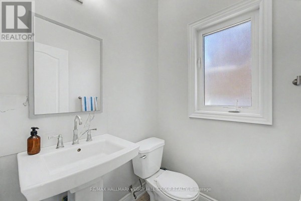 Powder room with a white pedestal sink, toilet, and silver faucet. - Upper - 53 Nathan Crescent, Barrie