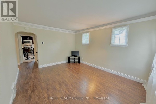 Living room with hardwood floors, neutral walls, two small windows, and an opening to the kitchen. - Upper - 538 Quebec Street, London East