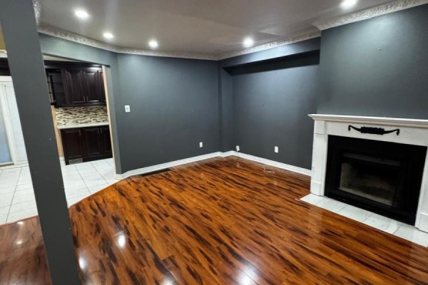 Living room with a fireplace, dark grey walls, and an opening to the kitchen. - Upper - 56 Overlord Crescent, Toronto