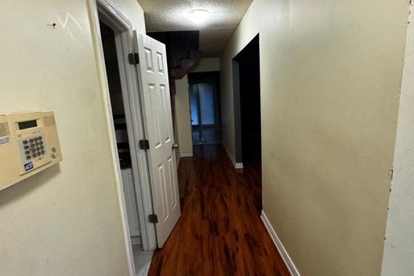 Hallway with light beige walls, dark brown laminate flooring, and several doors. - Upper - 56 Overlord Crescent, Toronto