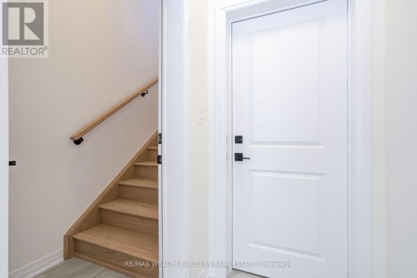 Interior entryway with a view of a wooden staircase with black railings and white walls. - Upper - 6 Thornbird Crescent, Brampton