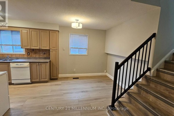 Kitchen area with light wood cabinets, white appliances, and adjacent dining space. - Upper - 67 Simmons Boulevard, Brampton
