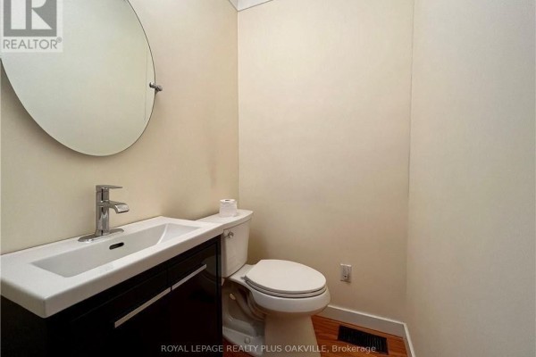 Powder room with a white pedestal sink, dark wood vanity, and a white toilet. - Upper - 694 Niagara Street, St  Catharines