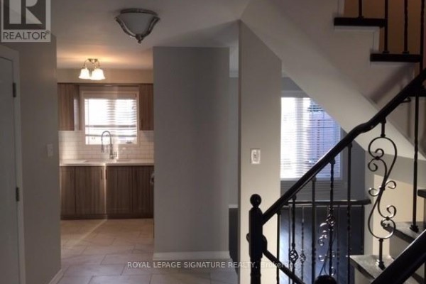 Interior hallway showing a staircase with black metal spindles and a glimpse of the kitchen. - Upper - 7092 Walworth Court, Mississauga