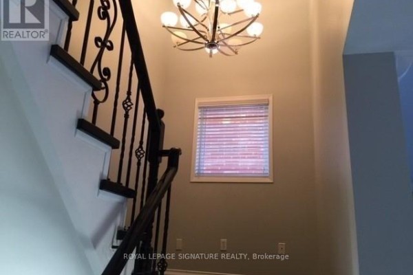View looking up a staircase with a decorative metal railing and a large chandelier overhead. - Upper - 7092 Walworth Court, Mississauga