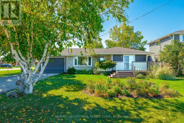 A wide shot of the house exterior, showing the driveway, lawn, and landscaping with trees. - Upper - 71 Lakeside Drive, Grimsby
