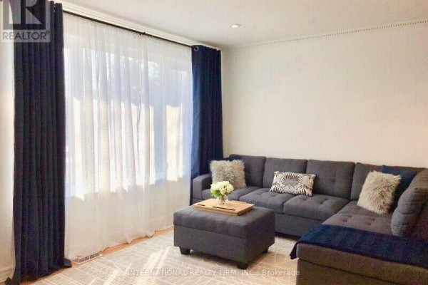 Living room with a dark grey sectional sofa, white sheer curtains, and dark blue drapes. - Upper - 77 Elise Terrace, Toronto