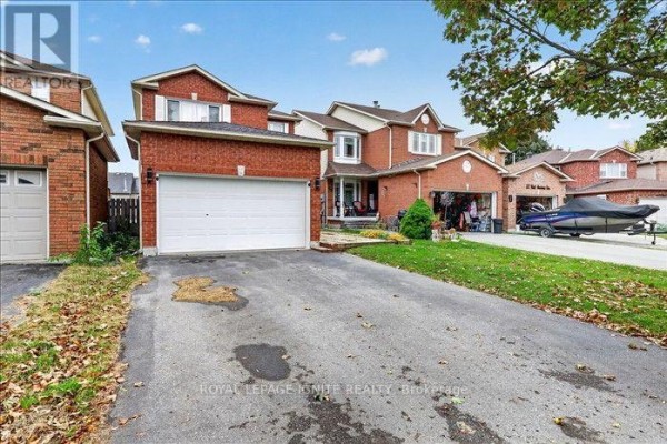 Street view showing a red brick house with a garage, driveway, and a boat on a trailer. - Upper - 8 Vail Meadows Crescent, Clarington