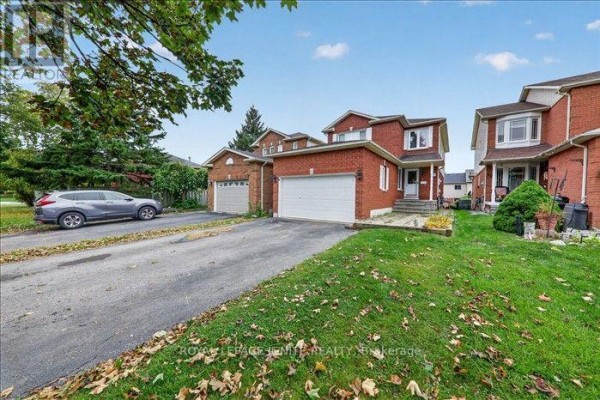 Side view of a red brick house showing the garage and driveway with a silver SUV parked. - Upper - 8 Vail Meadows Crescent, Clarington