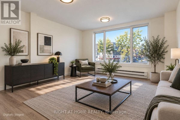 Living room with beige sofa, green armchair, dark wood sideboard, and large window. - Upper - 843 Danforth Avenue, Toronto