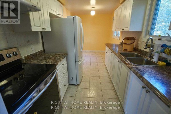 Galley kitchen with white cabinets, granite countertops, white appliances, and tiled floor. - Upper - 877 Thistle Down Circle, Mississauga