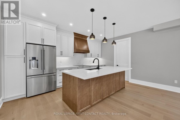 Kitchen with white cabinetry, stainless steel appliances, and a large island with a waterfall countertop. - Upper - 929 7th Line, Innisfil