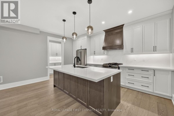 Kitchen features white cabinetry, a large island with sink, and wood accents. - Upper - 933 7th Line, Innisfil