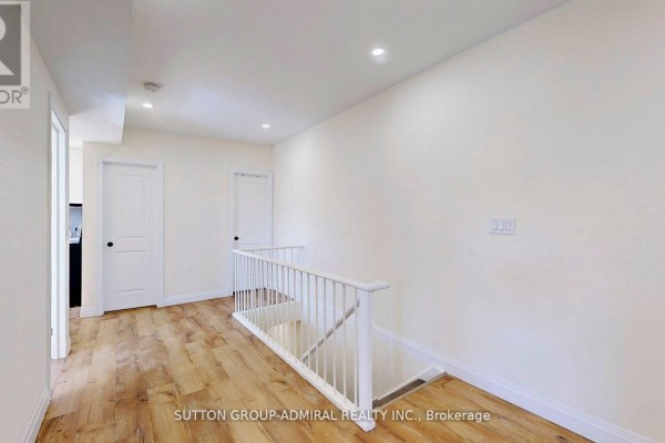 Upper hallway with white doors, a white railing, and light wood-look laminate flooring. - Upper 1 - 1930 Queen Street E, Toronto