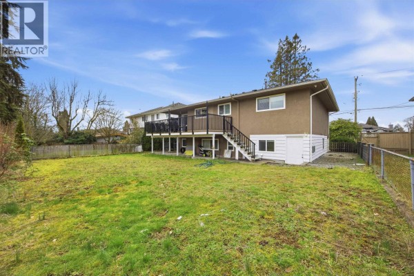 Rear exterior view of the house with a large backyard and a deck accessible by stairs. - Upper 1106 Duthie Avenue, Burnaby