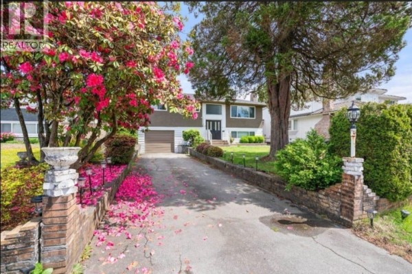 View of the house's driveway lined with brick pillars and blooming pink rhododendron trees. - Upper 1106 Duthie Avenue, Burnaby