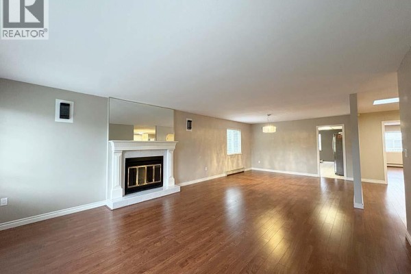Living room fireplace with mirrored wall and access to other rooms. - Upper 5225 Canada Way, Burnaby