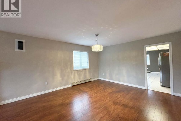 Dining area with a modern chandelier and view into the kitchen. - Upper 5225 Canada Way, Burnaby