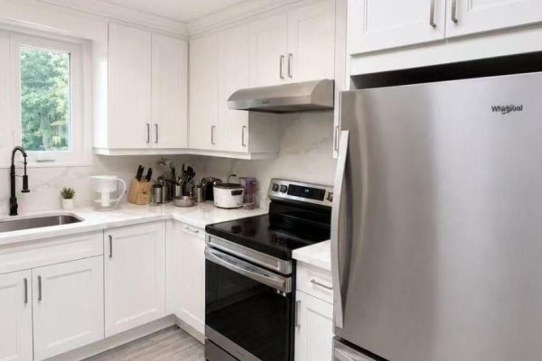 White kitchen with stainless steel appliances, including a refrigerator and stove, and marble countertops. - Upper 758 Bradley Avenue, London South