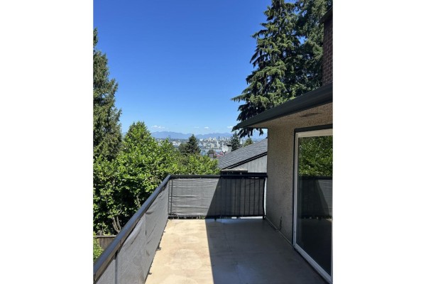 Deck overlooking a city skyline and distant mountains, with trees on the sides and a grey railing. - Upper 9655 Townline Diversion, Surrey