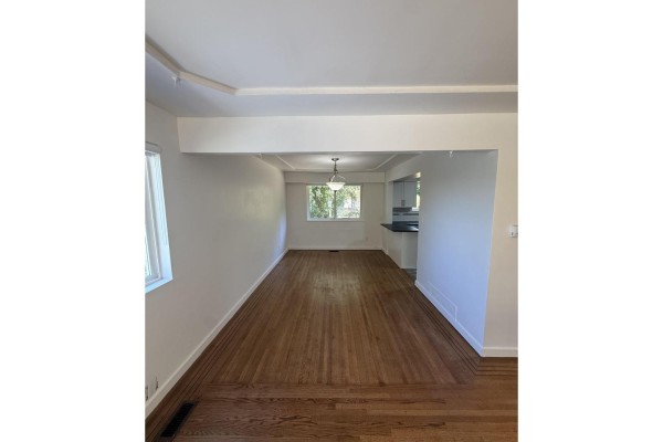 View from the living room through an opening into the dining room and kitchen area with hardwood floors. - Upper 9655 Townline Diversion, Surrey