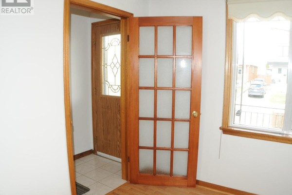 Interior view of a hallway with a wooden paneled door and a window to the outside. - Upper Floor - 49 Algoma Street, Toronto