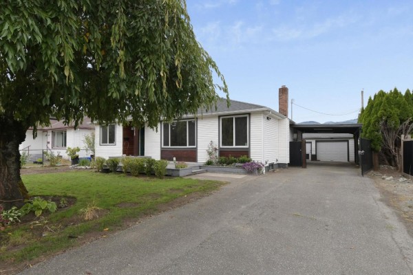 Side view of a white one-story house with a driveway and covered carport. - Upper House 46515 Portage Avenue, Chilliwack Proper East, Chilliwack