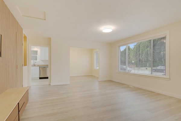 Living room with light wood laminate flooring, large windows, and view of kitchen. - Upper House 46515 Portage Avenue, Chilliwack Proper East, Chilliwack