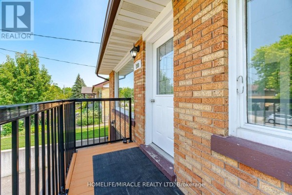 Close-up of the wooden deck and front door of a red brick bungalow with black railings. - Upper Level - 199 Allen Street E, Waterloo