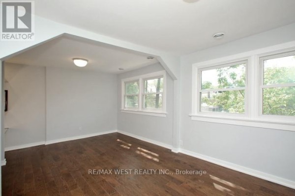 Living room with light blue walls, hardwood floors, and large windows. - Upper Level - 420 Annette Street, Toronto