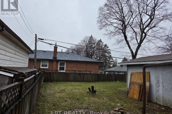 A wet asphalt driveway runs between two brick houses with wooden fences on either side. - Upper Only - 478 Brimley Road, Toronto