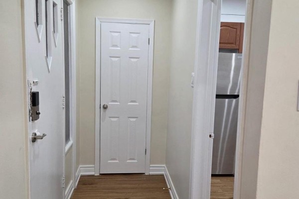 A small kitchen area with a stainless steel refrigerator, dark wood cabinets, and a doorway. - Upper Only - 478 Brimley Road, Toronto