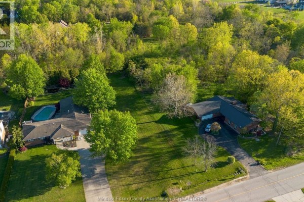 Aerial view of homes surrounded by trees and snow-covered land, with wind turbines in distance. - V/l Bissonnette Lane, Lakeshore