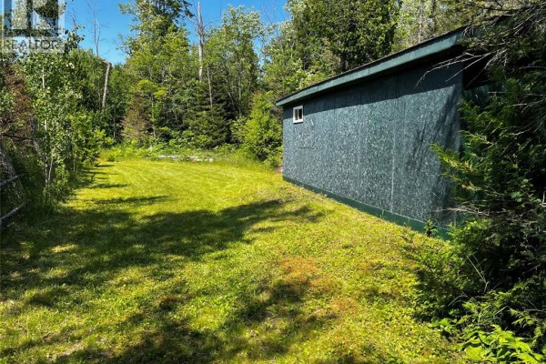 Green shed with a white door and small windows sits in a mowed yard with trees. - V/l Warner Bay Road, Bruce County
