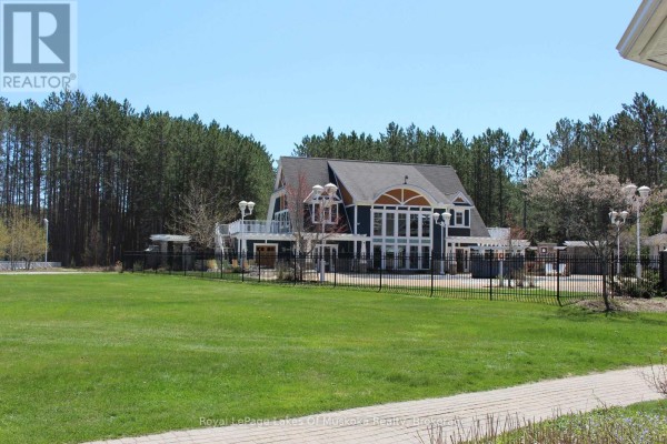 Exterior view of a large house with a fenced yard and surrounding trees. - V1, W1 - 1020 Birch Glen Road, Lake Of Bays