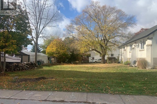 Wide view of a residential lot with a shed, greenhouse, large tree, and houses on either side. - W/s Fielden Avenue, Port Colborne
