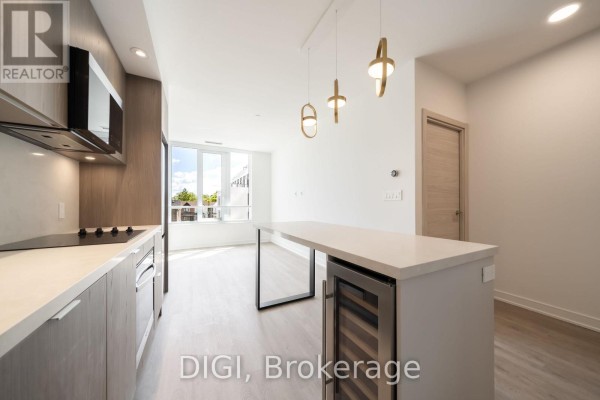 Kitchen island with built-in wine fridge and view towards living area and windows. - W320 - 485 Perth Avenue, Toronto