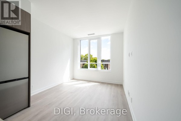 Empty living space with large windows showing trees and adjacent building. - W320 - 485 Perth Avenue, Toronto