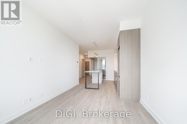 Open concept living area with modern kitchen and island, looking towards entrance. - W320 - 485 Perth Avenue, Toronto
