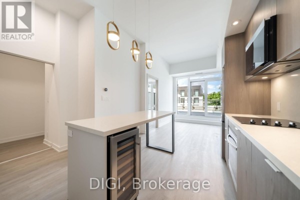 Kitchen island with wine fridge, view of living area and balcony with building exterior. - W426 - 485 Perth Avenue, Toronto