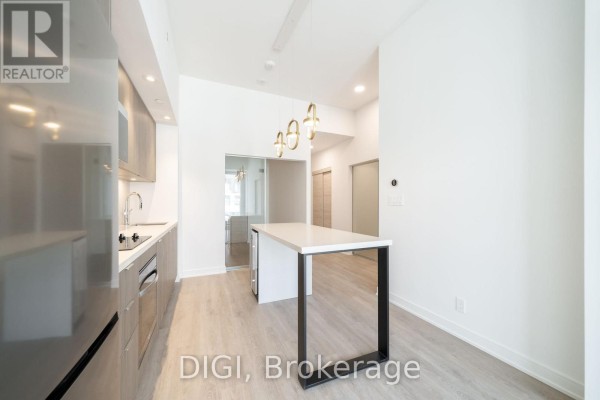 Kitchen with modern cabinets, island, and view of a hallway with sliding glass doors. - W426 - 485 Perth Avenue, Toronto