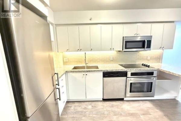 Living area with grey flooring, white walls, a dark media unit, and a sliding glass door. - W804 - 565 Wilson Avenue W, Toronto