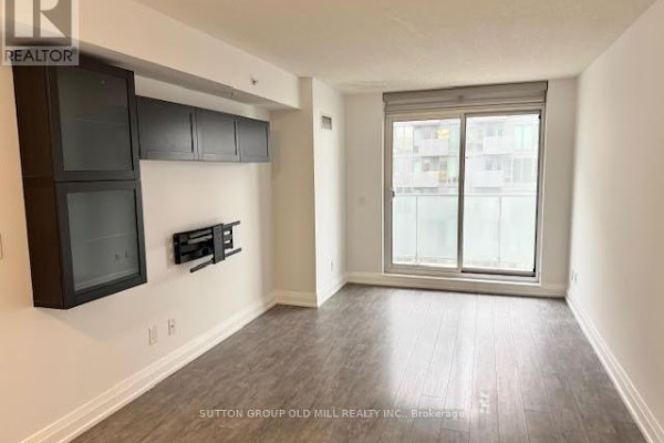 Bright living room with grey wood-look flooring, a large window with frosted glass, and city views. - W804 - 565 Wilson Avenue W, Toronto