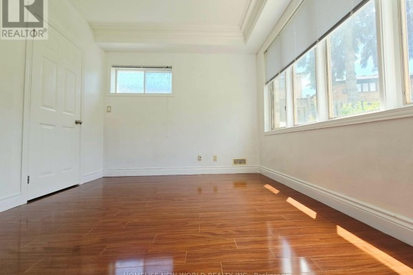 Empty room with light wood flooring, white walls, and a large bay window. - Walkout Bsm - 122 Centennial Road, Toronto