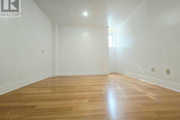 Empty room with light wood flooring, white walls, and a small window. - Walkout Bsm - 122 Centennial Road, Toronto