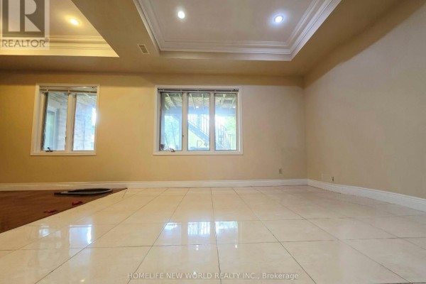 Large basement room with tiled flooring, beige walls, and windows looking outside. - Walkout Bsm - 122 Centennial Road, Toronto