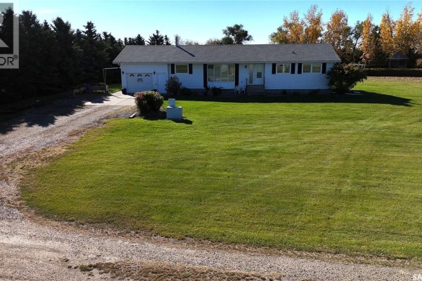 Front view of a white residential house with a long driveway, attached garage, and well-kept lawn. - Wallace Acreage, Buffalo Rm No  409