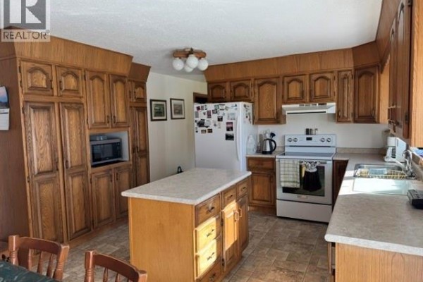Kitchen featuring light oak cabinetry, a center island with storage, a white refrigerator, and a white stove. - Wallace Acreage, Buffalo Rm No  409