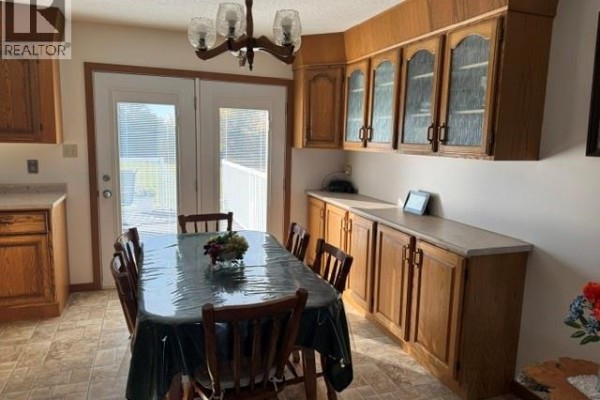 Dining area with a wooden table set for six, surrounded by light oak cabinetry and double doors leading outside. - Wallace Acreage, Buffalo Rm No  409